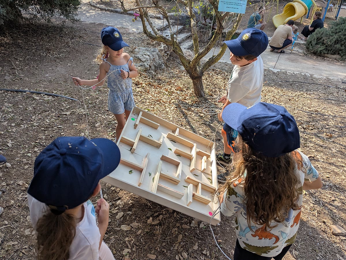 ארבעה ילדים מסביב לפאזל עץ גדול בחוץ - שיתוף פעולה ועבודת צוות בפעילות סדנה בטבע